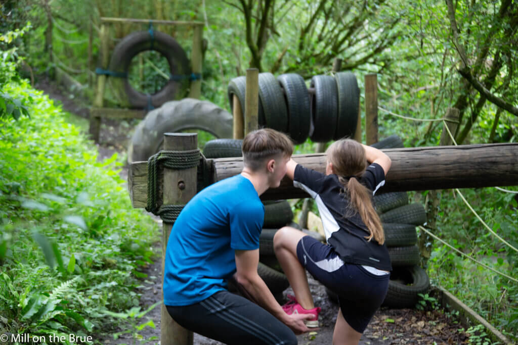 Boy helping girl complete assault course